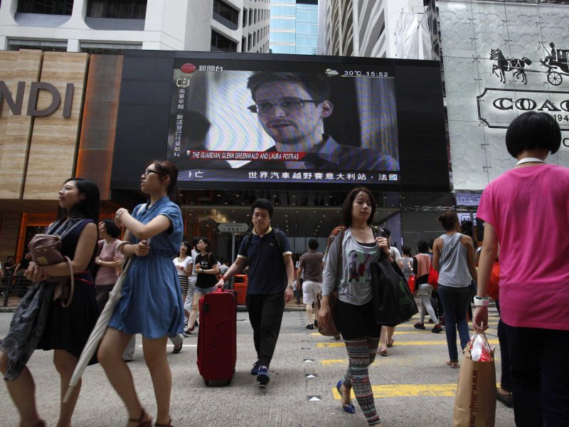 A monitor over a Hong Kong street informs a crowd that Edward Snowden has left China Credit: Business Insider
